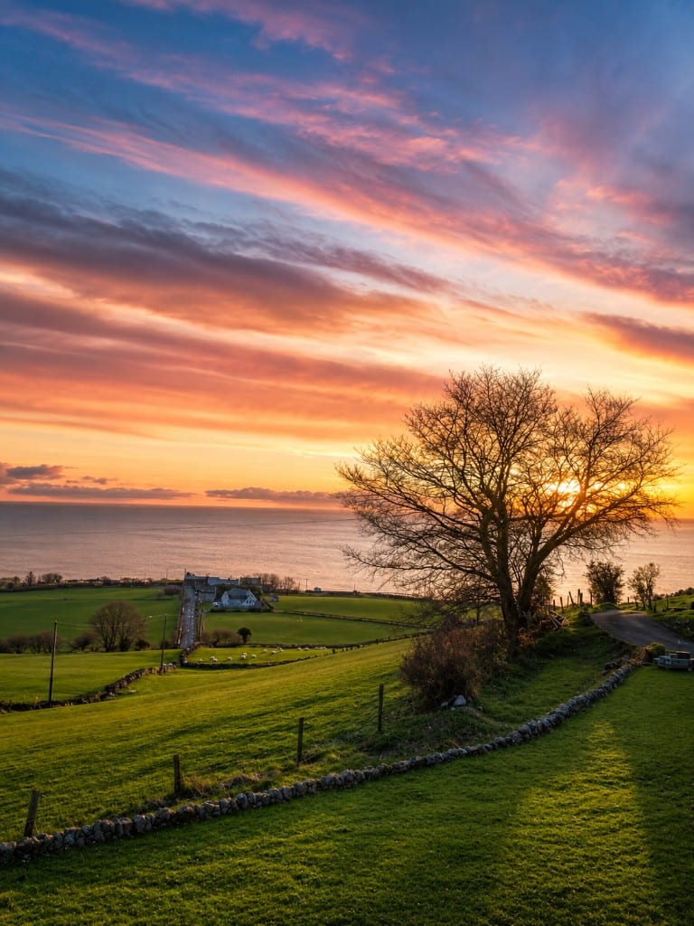 Sunset over green fields and the Antrim coast near Drumnacross House